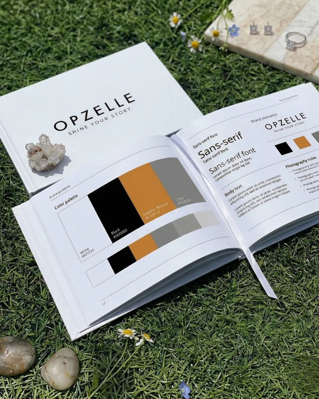ספר המותג של OPZELLE פתוח על דשא, עם פלטת הצבעים, הפונטים והלוגו